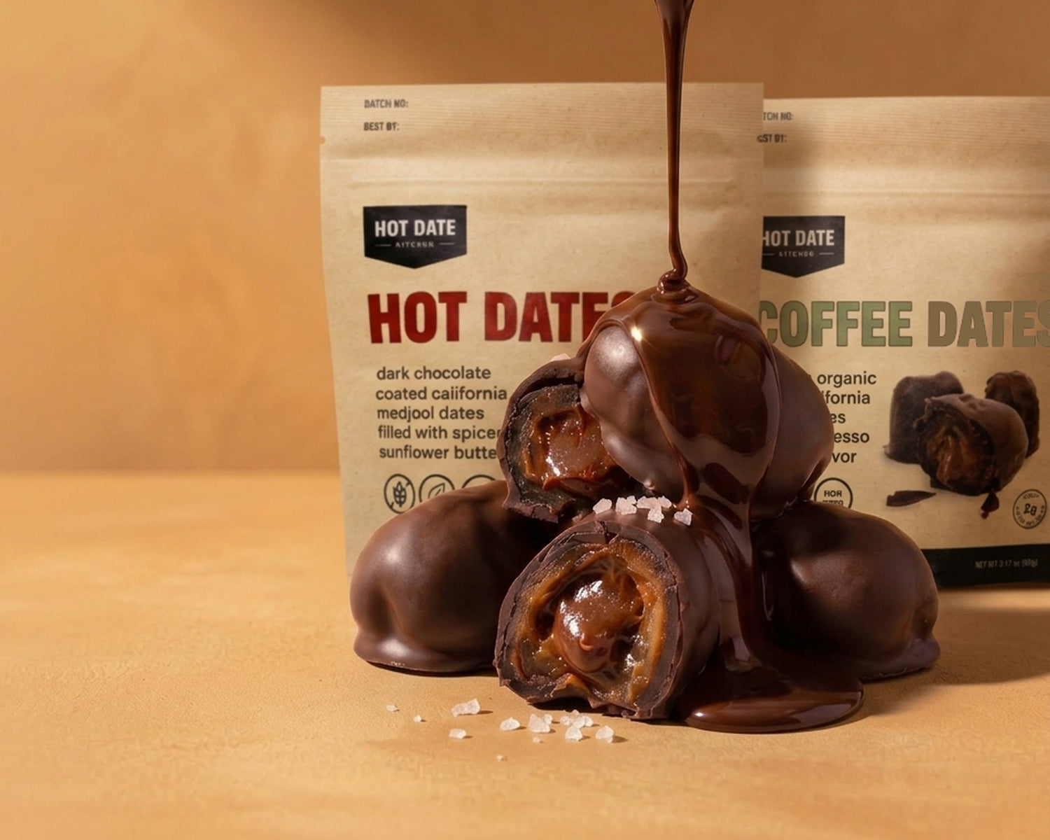Melted dark chocolate pouring over a stack of chocolate covered Medjool dates, two of them split open to show the spiced sunflower butter filling and flakes of sea salt